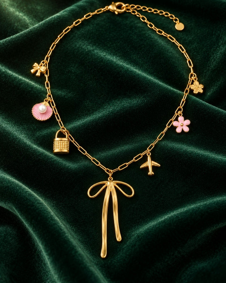 Elli Jewellery gold plated charm necklace featuring a bow, shell, lock, airplane, and flower charms on green velvet.