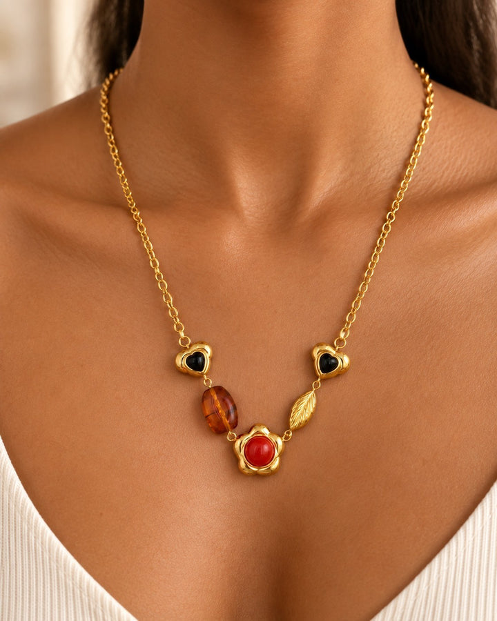 Elli Jewellery gold plated chain necklace featuring black heart, amber, and red flower charms on a model
