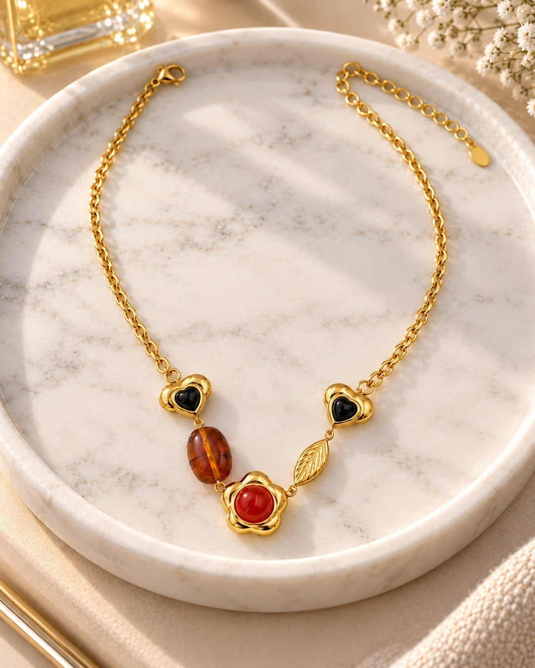 Elli Jewellery gold plated chain necklace featuring heart, amber, and flower charms on a marble tray.