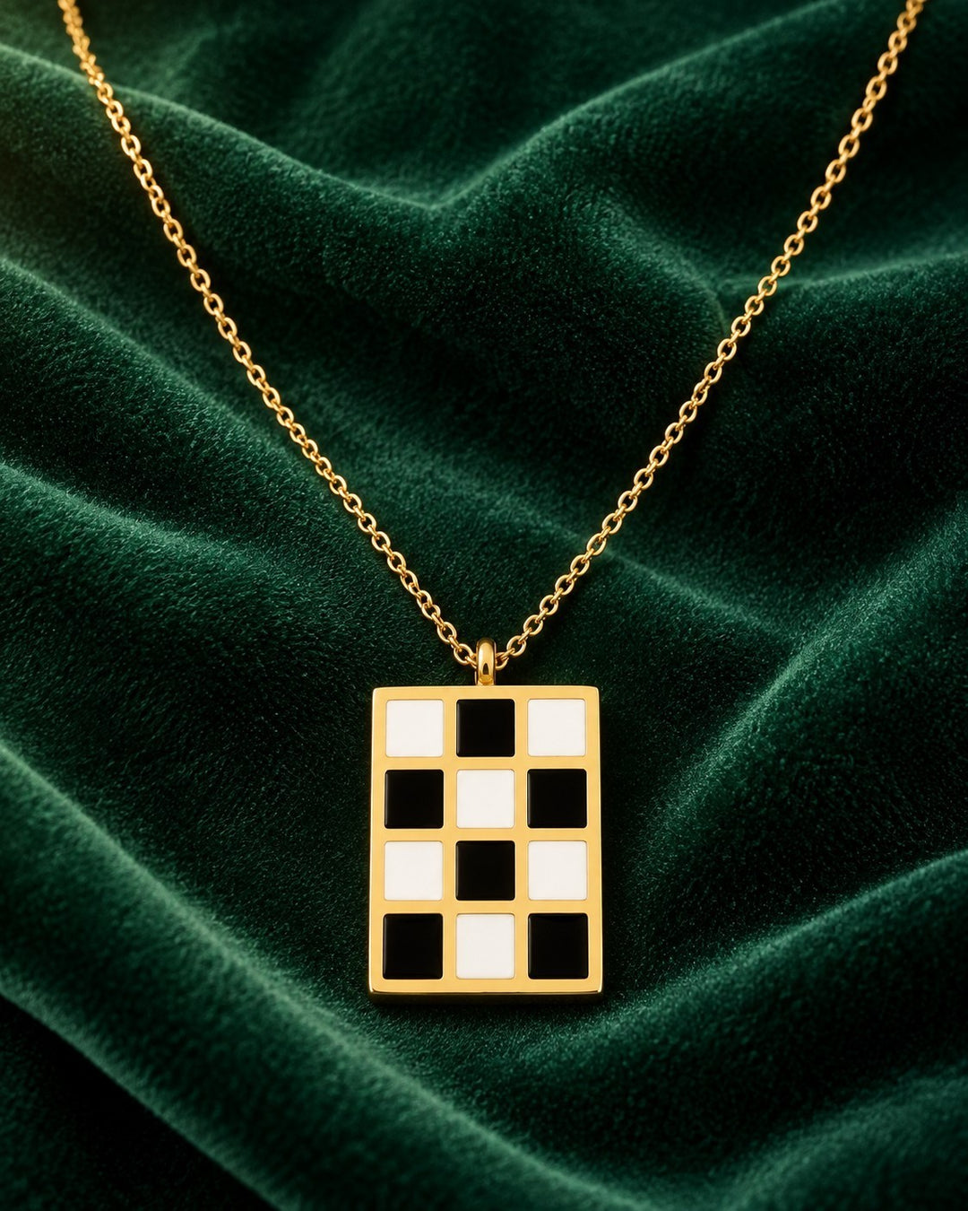 Elli Jewellery gold-plated rectangular pendant necklace featuring a black and white checkered pattern on green velvet.