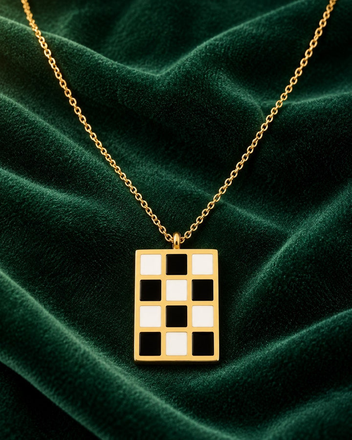 Elli Jewellery gold-plated rectangular pendant necklace featuring a black and white checkered pattern on green velvet.