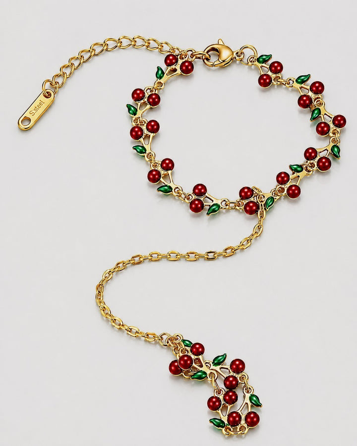 Elli Jewellery gold plated hand chain bracelet featuring vibrant red cherry charms and green leaves on a delicate chain