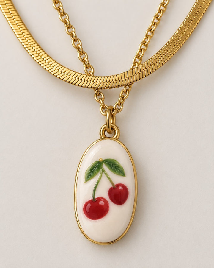 Elli Jewellery gold plated layered snake chain necklace featuring an oval pendant with a red cherry charm design.