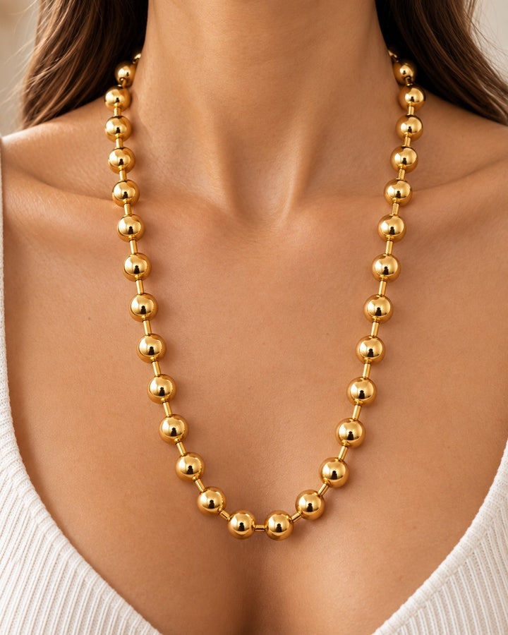 Elli Jewellery gold plated chunky ball chain necklace worn by a woman in a white top for a statement look.