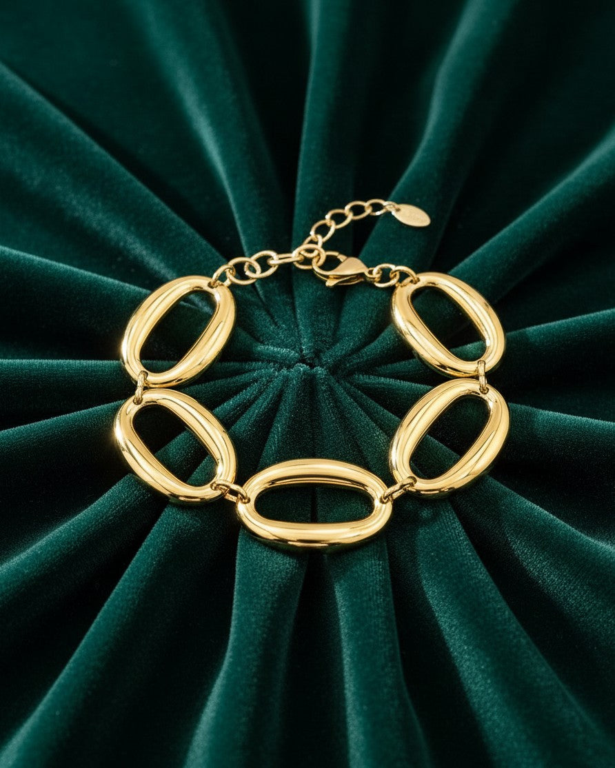 Elli Jewellery gold plated chunky chain link bracelet with oversized oval links on a dark green velvet background