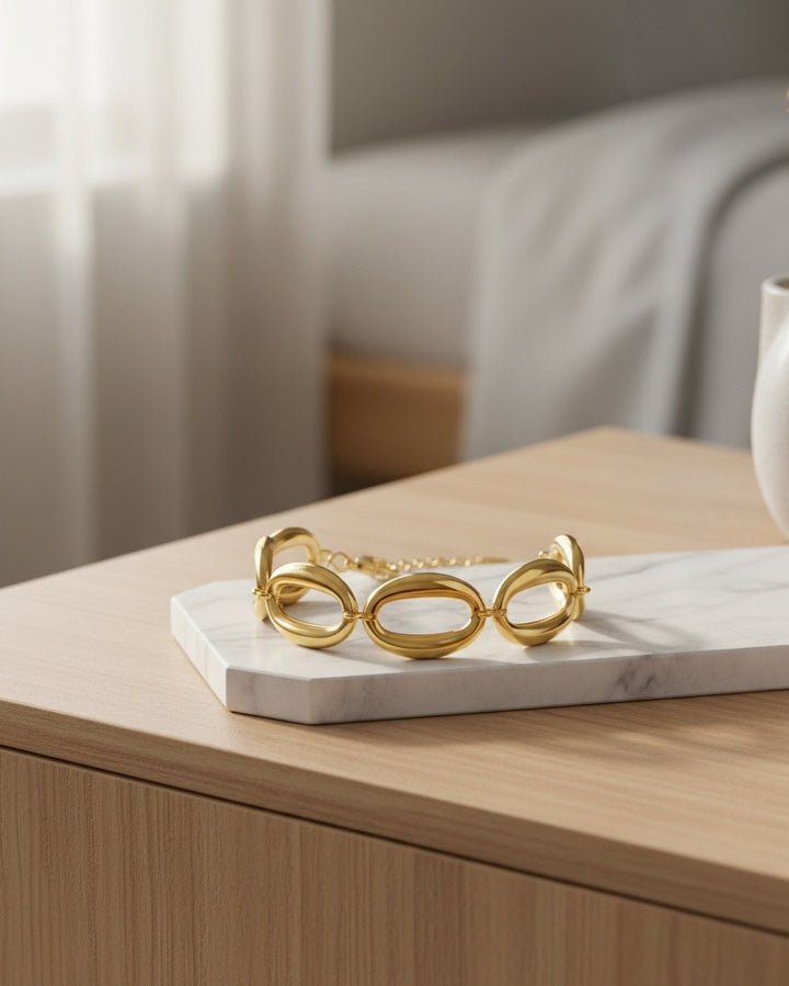 Elli Jewellery gold plated chunky chain link bracelet resting on a white marble surface in a bright bedroom setting.