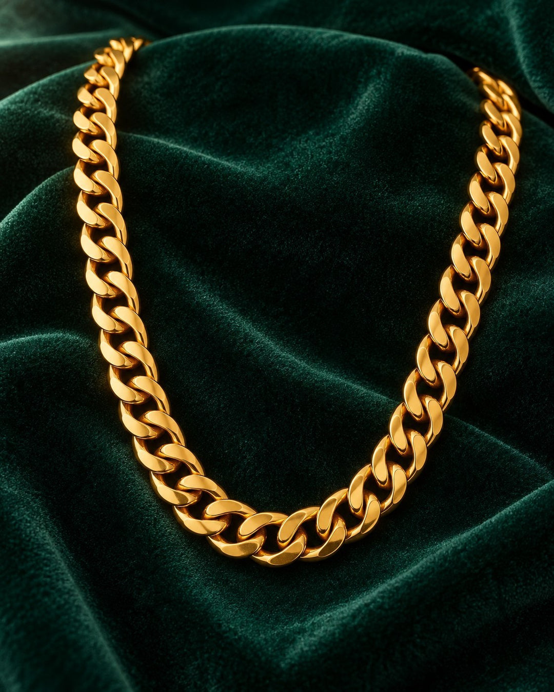 Elli Jewellery gold plated chunky Cuban link chain necklace resting on a dark green velvet fabric background.