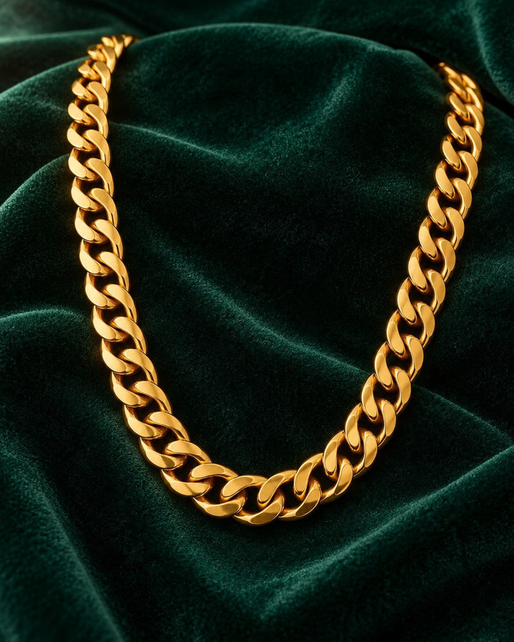 Elli Jewellery gold plated chunky Cuban link chain necklace resting on a dark green velvet fabric background.
