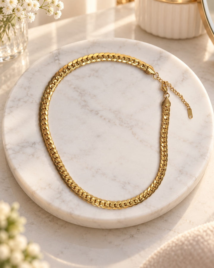 Elli Jewellery gold plated chunky curb chain necklace with a waterproof and tarnish-free finish on a marble display.