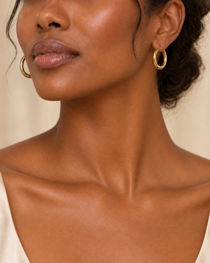 Elli Jewellery 3cm gold plated chunky hoop earrings with a textured surface worn by a woman