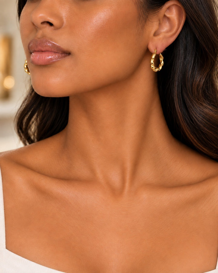 Elli Jewellery gold plated chunky geometric hoop earrings worn by a model with dark wavy hair