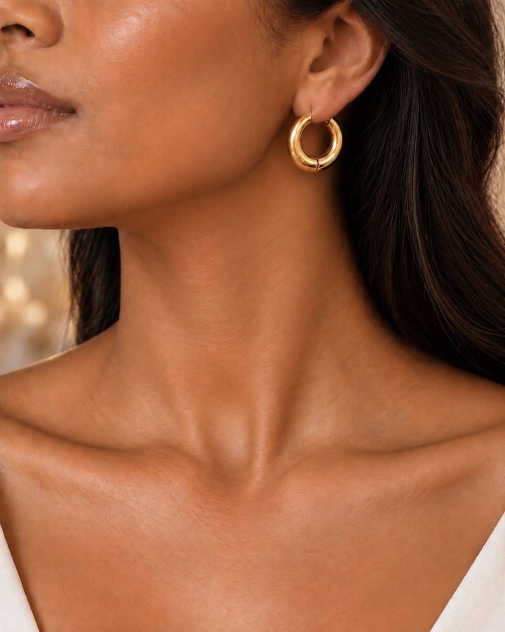 Elli Jewellery gold plated chunky hoop earrings worn by a model, featuring a smooth polished finish and 2.5cm size.