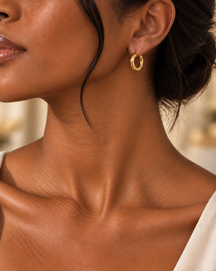 Elli Jewellery gold plated chunky 2cm hoop earrings worn by a woman with an elegant updo hairstyle