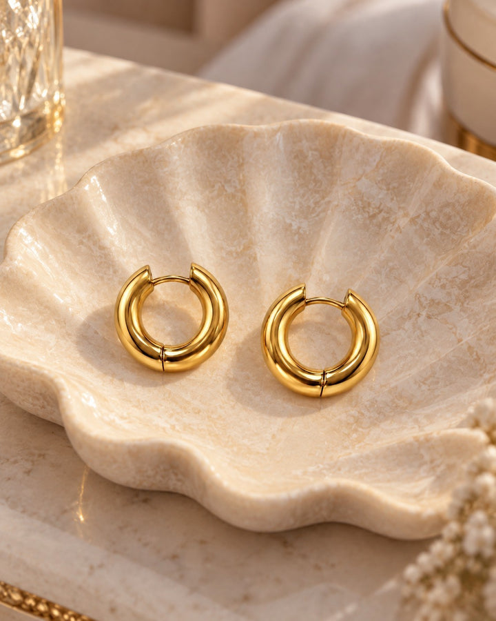 Elli Jewellery gold plated chunky 2cm hoop earrings resting in a decorative shell dish