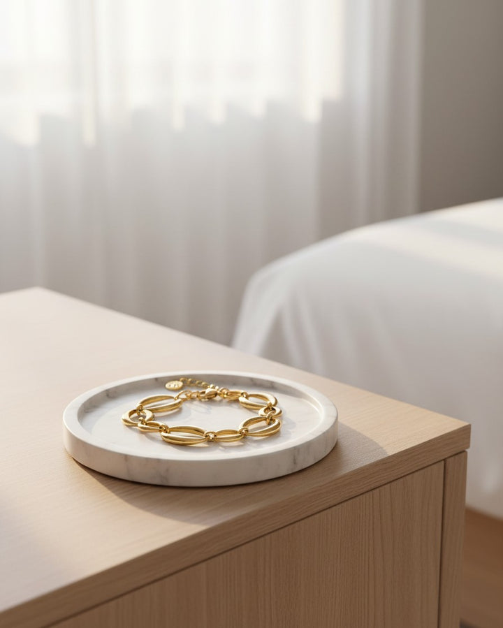 Elli Jewellery gold plated chunky link chain bracelet with charm detail resting on a white marble tray