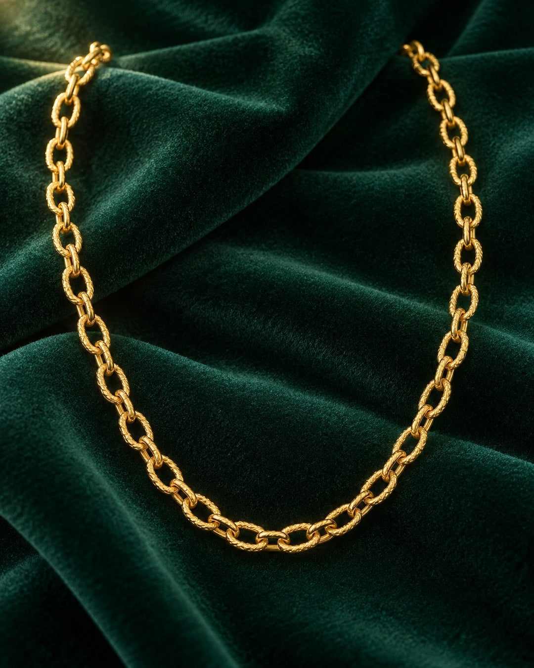 Elli Jewellery gold plated chunky link chain necklace resting on a dark green velvet fabric background.