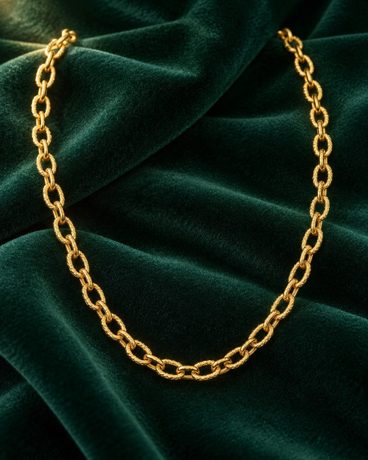 Elli Jewellery gold plated chunky link chain necklace resting on a dark green velvet fabric background.