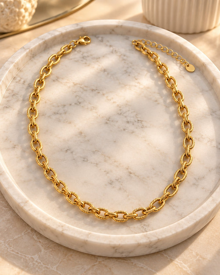 Elli Jewellery gold plated chunky link chain necklace with textured interlocking links on a marble display tray.