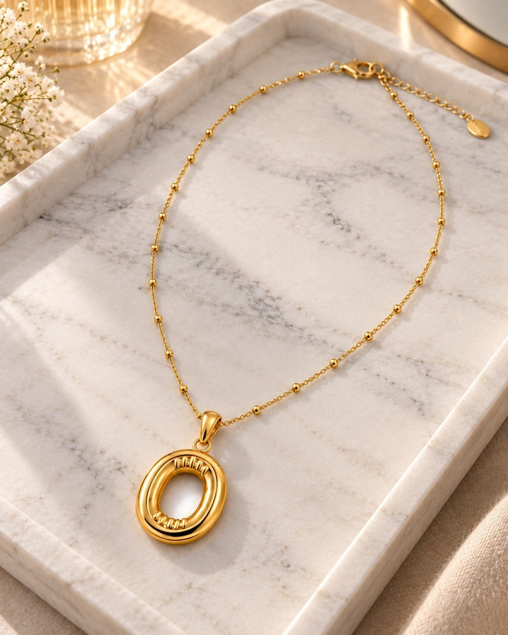 Elli Jewellery gold plated chunky initial O pendant necklace on a marble tray with delicate beaded chain detail.