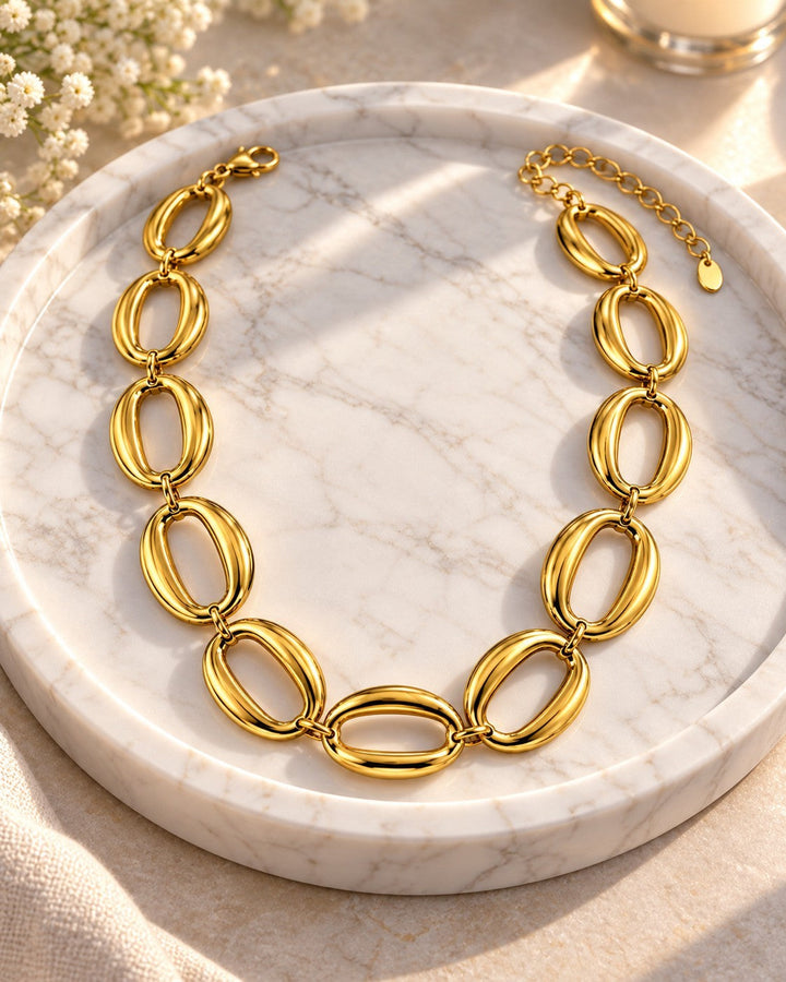 Elli Jewellery gold plated chunky oval link chain necklace resting on a white marble tray with soft sunlight.