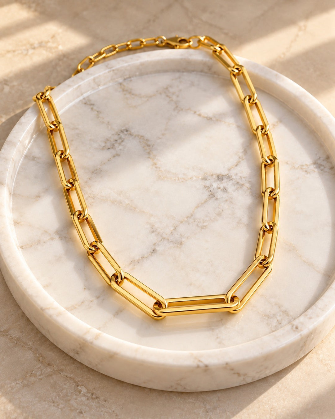 Elli Jewellery gold plated chunky paper link chain necklace resting on a white marble tray