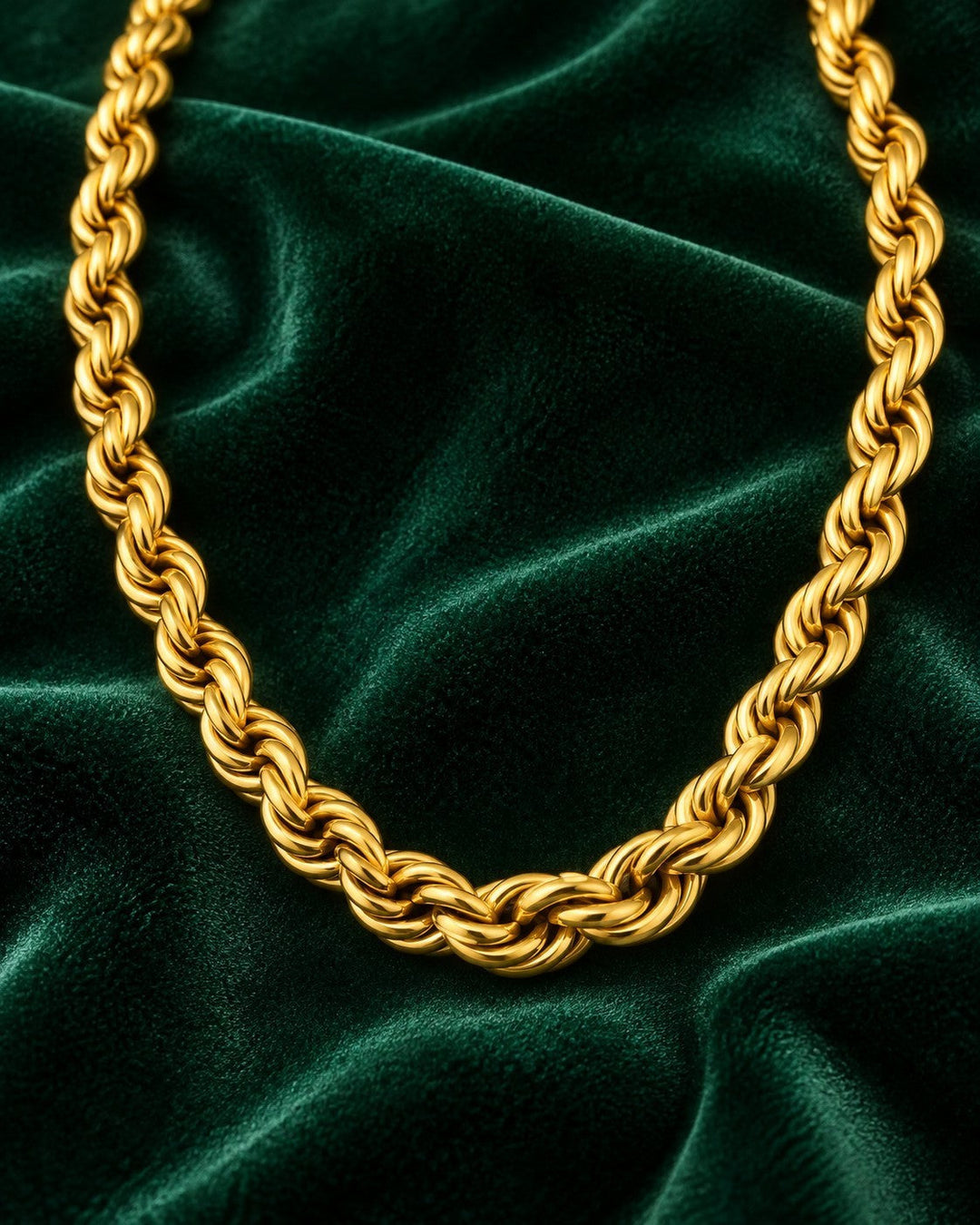 Elli Jewellery gold plated chunky rope chain necklace resting on a dark green velvet background.