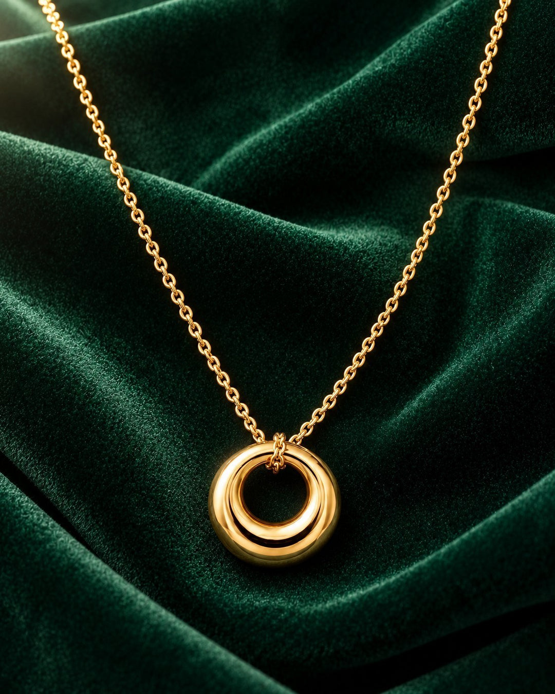 Elli Jewellery gold plated waterproof circle pendant necklace on a luxurious dark green velvet background