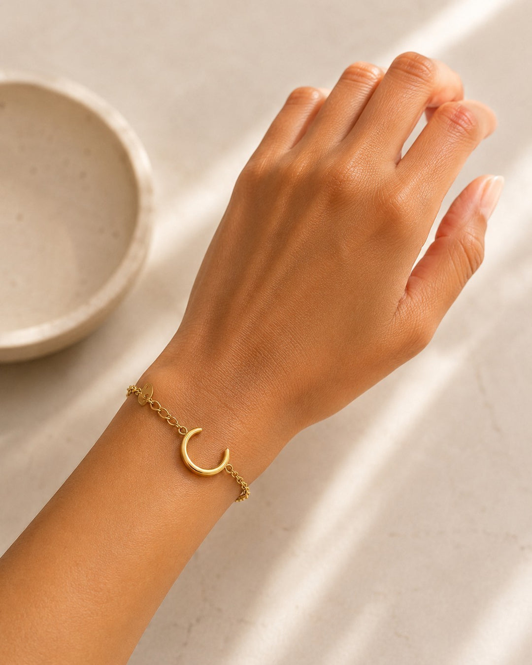 Elli Jewellery gold plated minimalist chain bracelet with a crescent moon charm worn on a woman's wrist