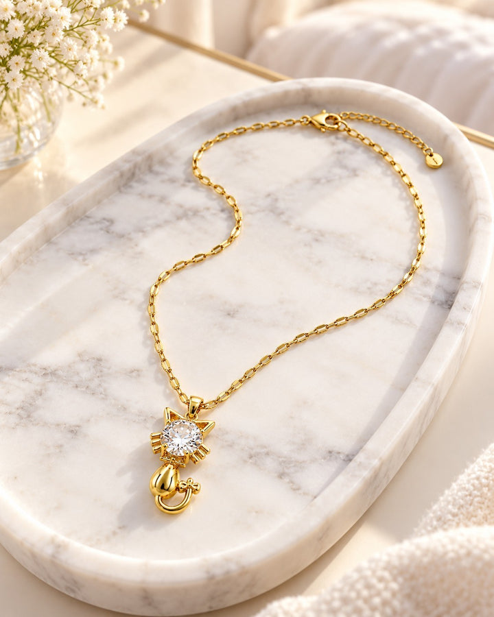 Elli Jewellery gold plated cat pendant necklace with a sparkling crystal center on a marble tray.