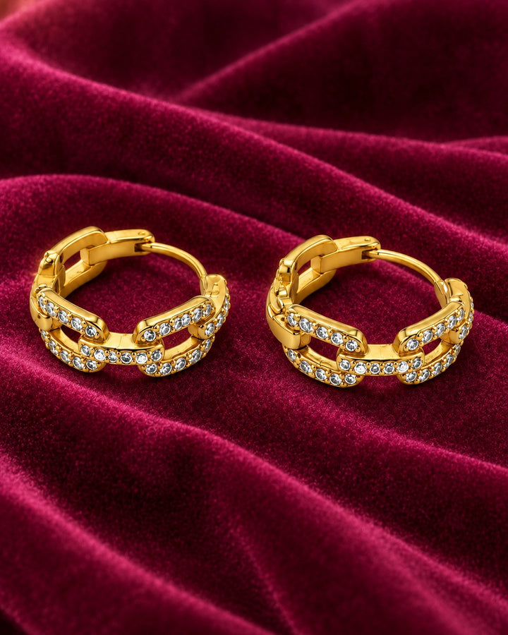 Elli Jewellery gold plated chunky chain link hoop earrings with sparkling crystals on a deep red velvet background