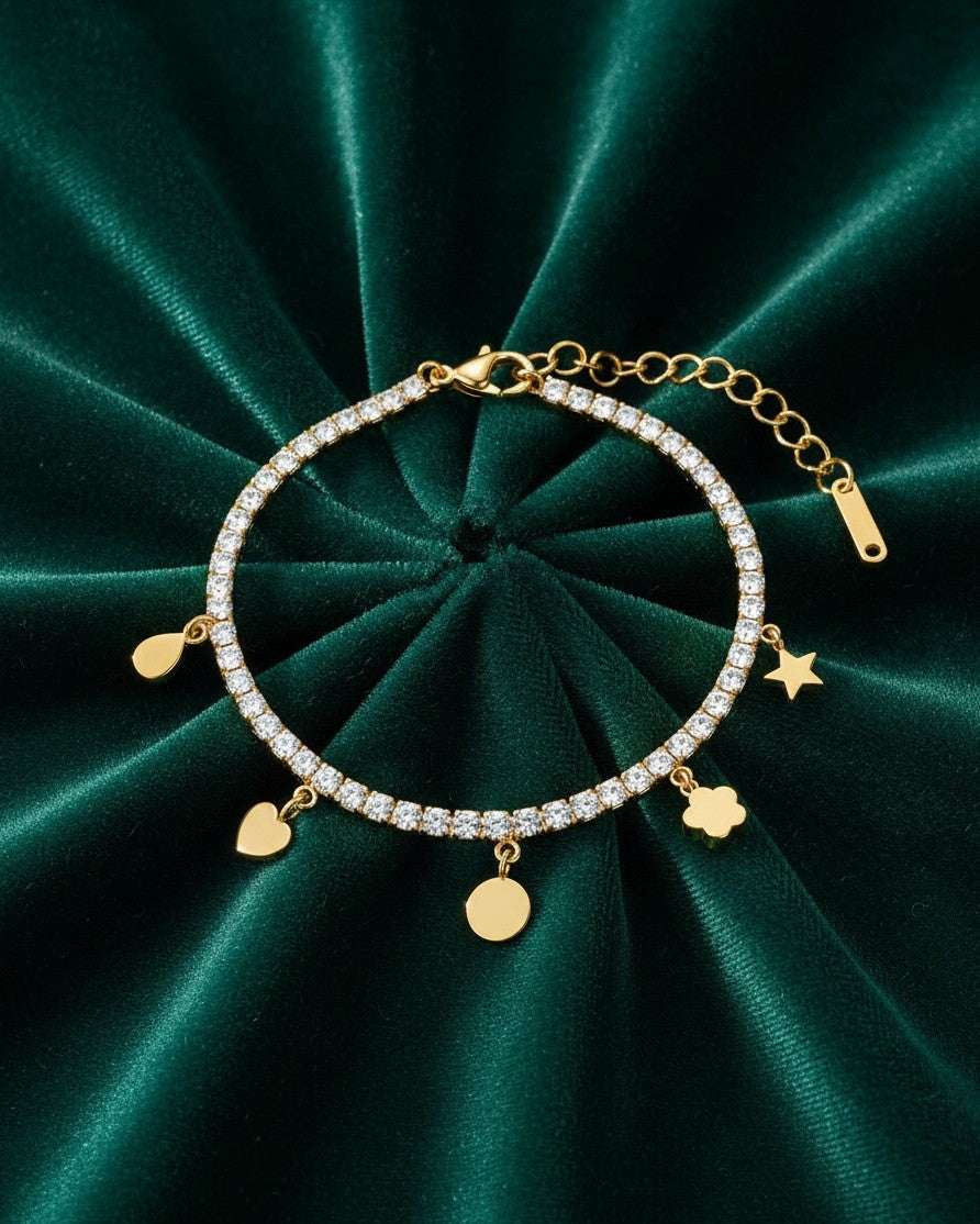 Elli Jewellery gold plated waterproof charm bracelet with crystal accents on a dark green velvet background