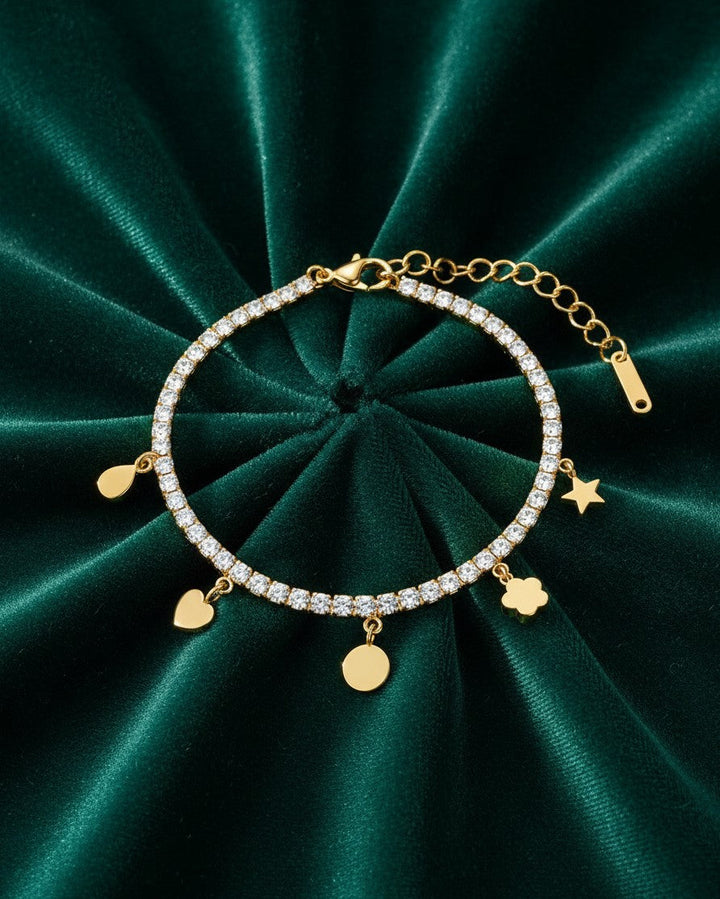 Elli Jewellery gold plated waterproof charm bracelet with crystal accents on a dark green velvet background