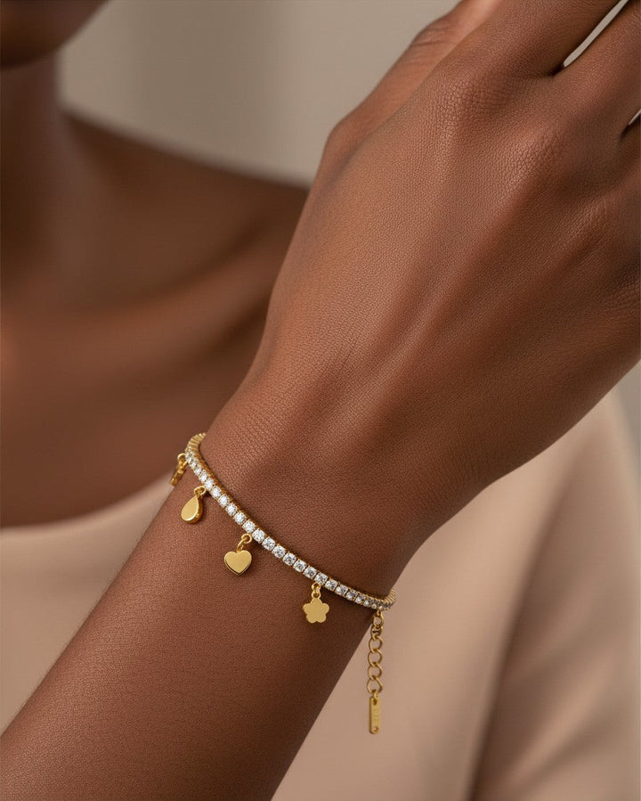 Elli Jewellery gold plated waterproof charm bracelet with crystal accents worn on a model's wrist