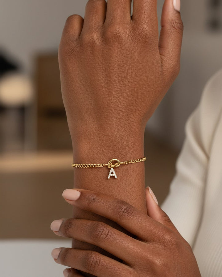 Elli Jewellery gold-plated chain bracelet featuring a sparkling crystal letter A charm worn on a woman's wrist