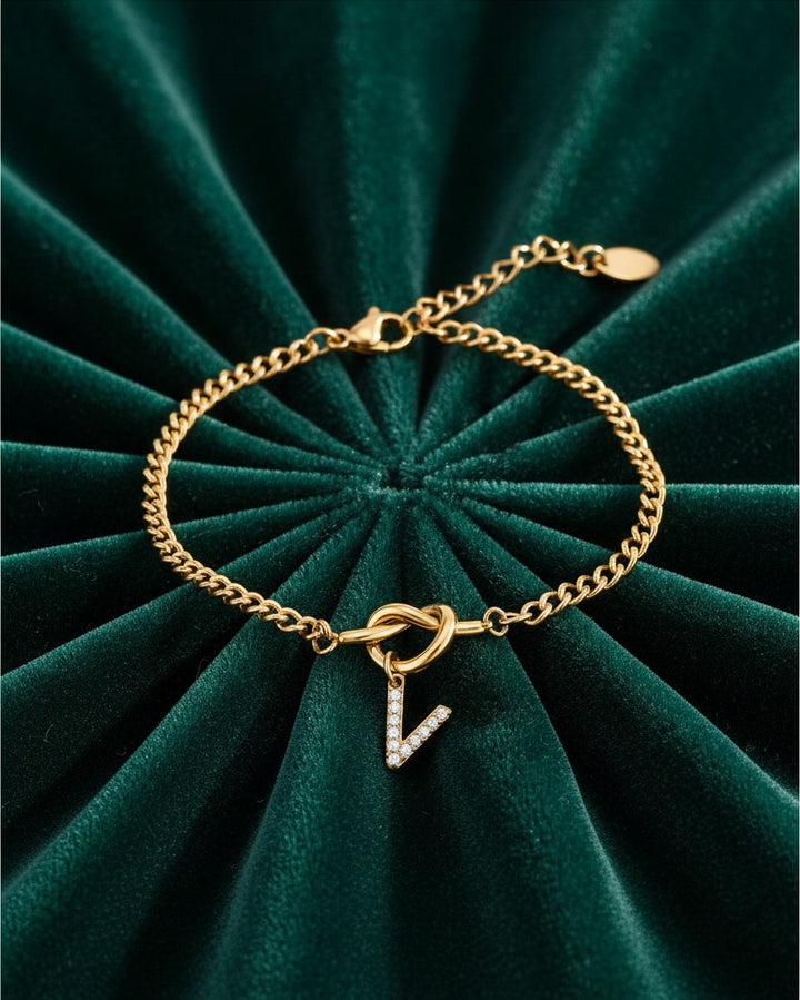 Elli Jewellery gold plated V-shape diamante bracelet with clear crystals on a dark green velvet background.