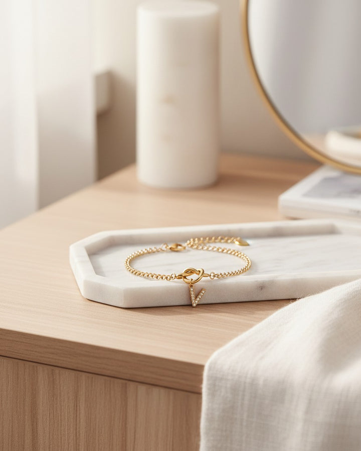 Elli Jewellery gold plated waterproof bracelet with a crystal-encrusted V-shape charm on a marble tray