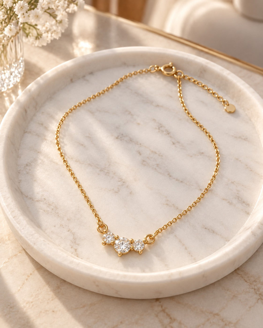 Elli Jewellery gold plated necklace featuring three sparkling cubic zirconia stones on a delicate chain on marble