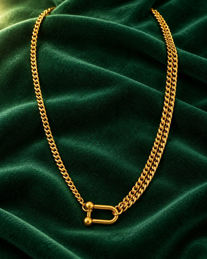 Elli Jewellery gold plated waterproof half layered curb chain necklace with a distinctive shackle clasp on green velvet