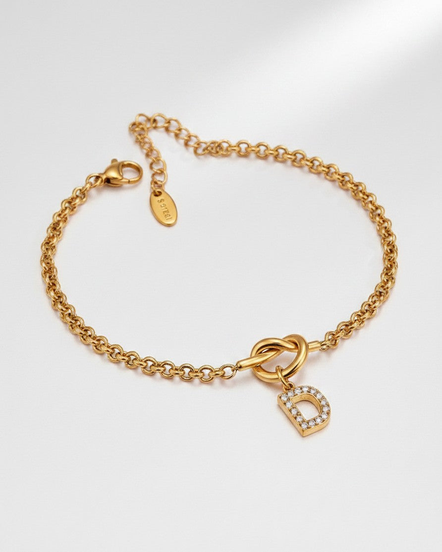 Elli Jewellery gold plated waterproof chain bracelet featuring a crystal-encrusted letter D charm on a knot detail.