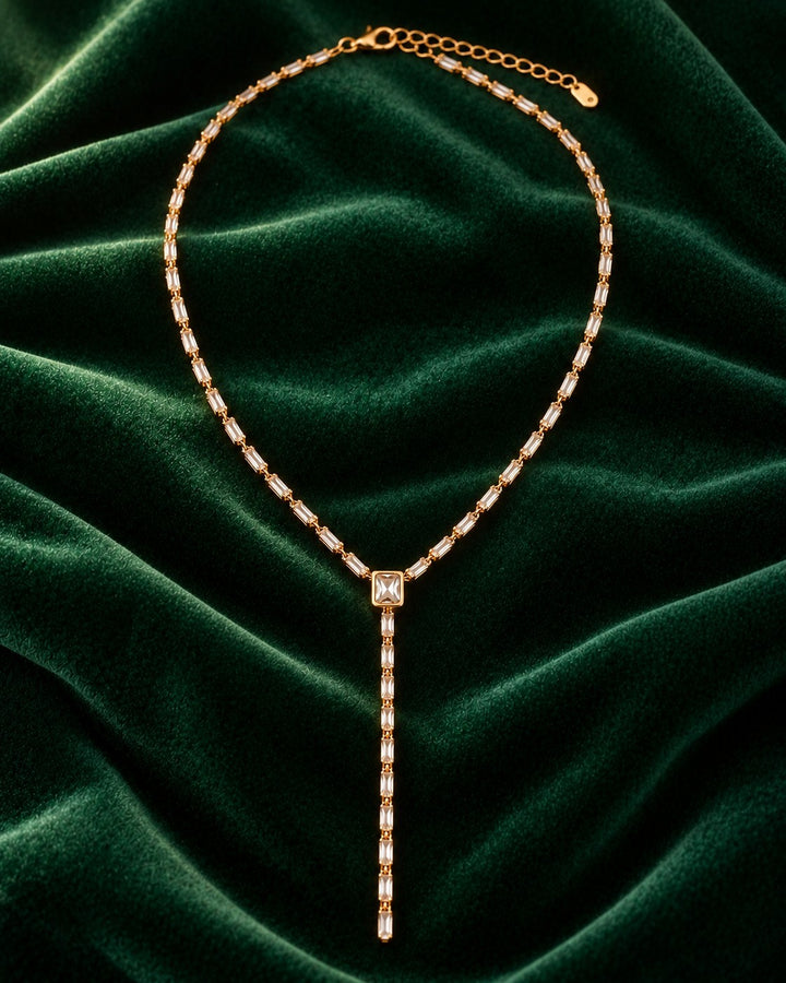 Elli Jewellery gold plated long necklace featuring baguette cut diamante crystals on a dark green velvet background