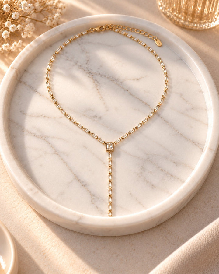 Elli Jewellery gold plated long chain necklace featuring delicate diamante crystal stones on a white marble tray.