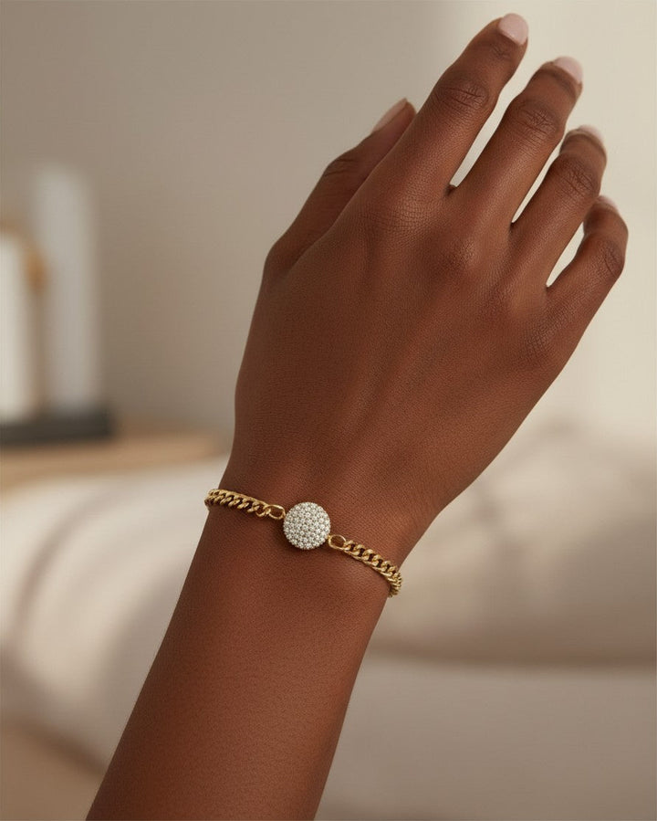 Elli Jewellery gold plated curb chain bracelet featuring a round diamanté pendant worn on a model's wrist