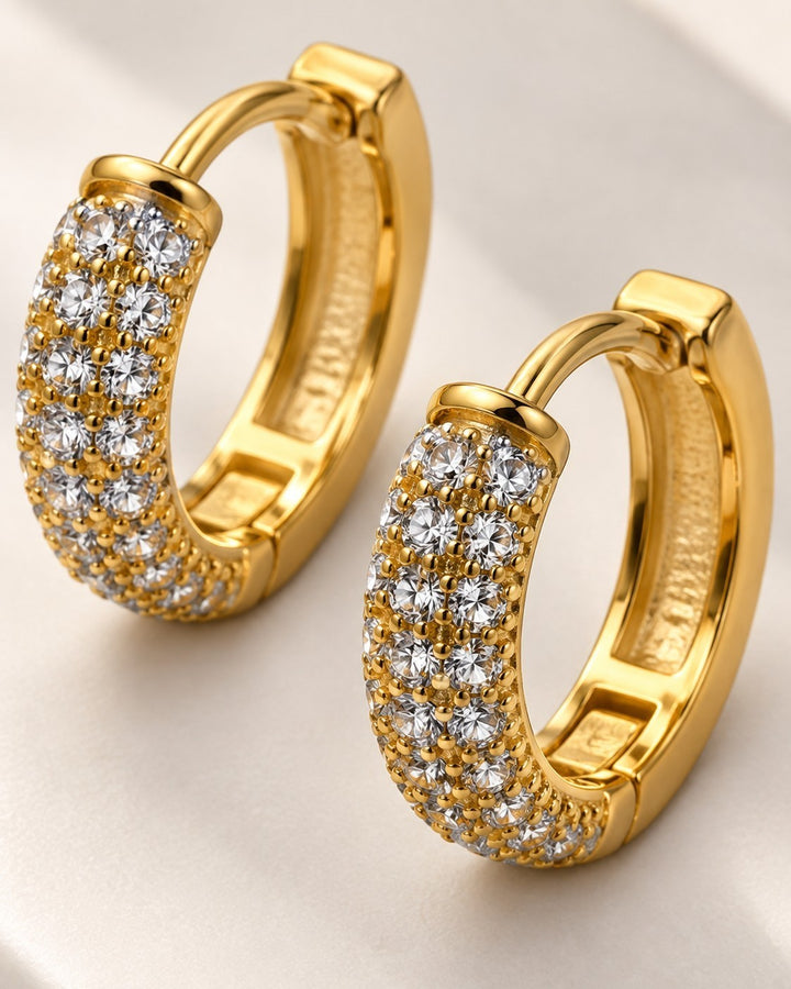 Elli Jewellery gold plated huggie hoop earrings featuring rows of sparkling diamanté stones on a white background.