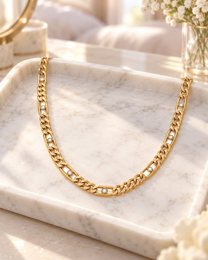 Elli Jewellery gold plated link chain necklace featuring sparkling diamante crystals on a marble tray.