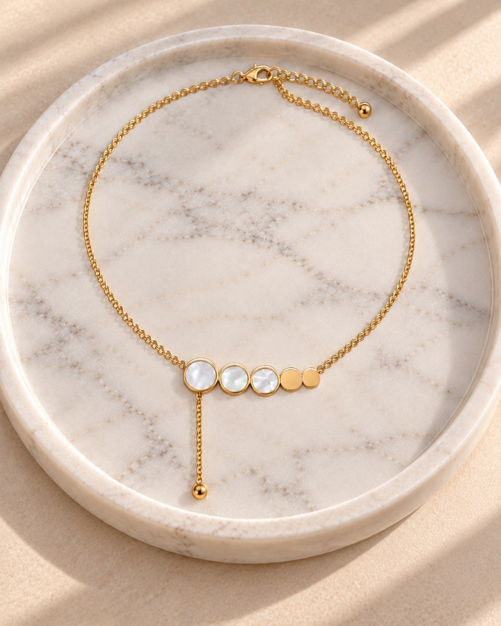 Elli Jewellery gold plated necklace featuring mother of pearl and gold discs on a delicate chain on a marble tray.