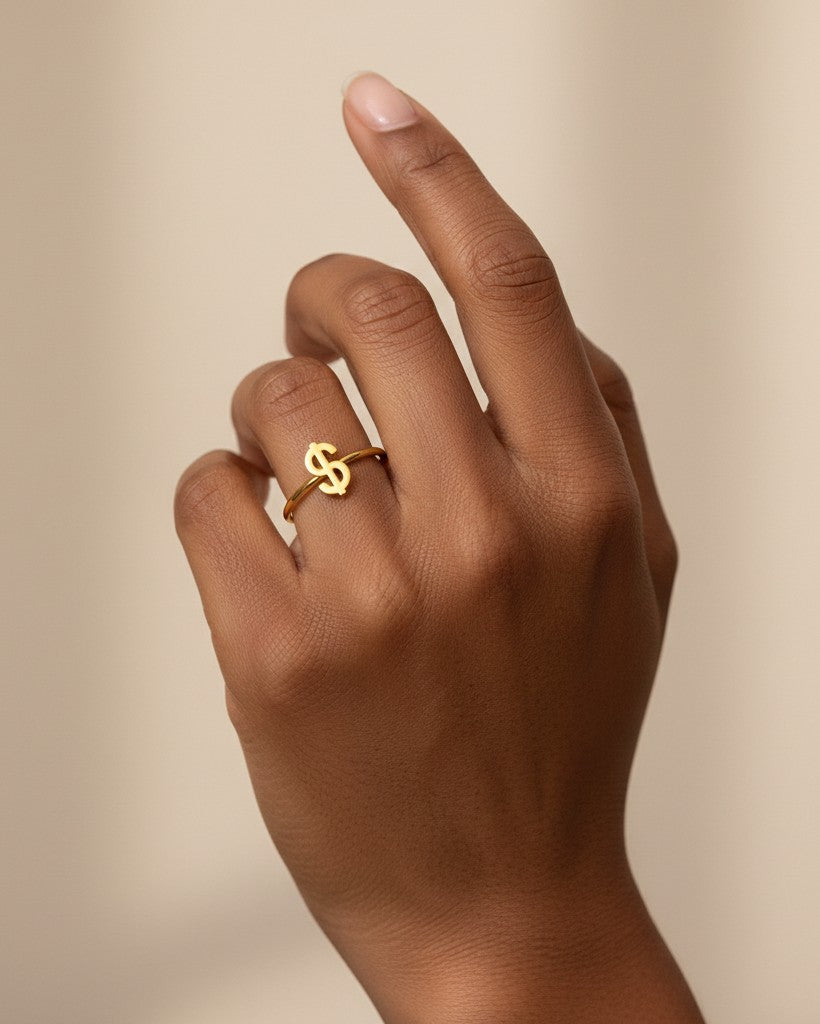 Elli Jewellery gold plated waterproof statement ring featuring a dollar sign symbol worn on a finger