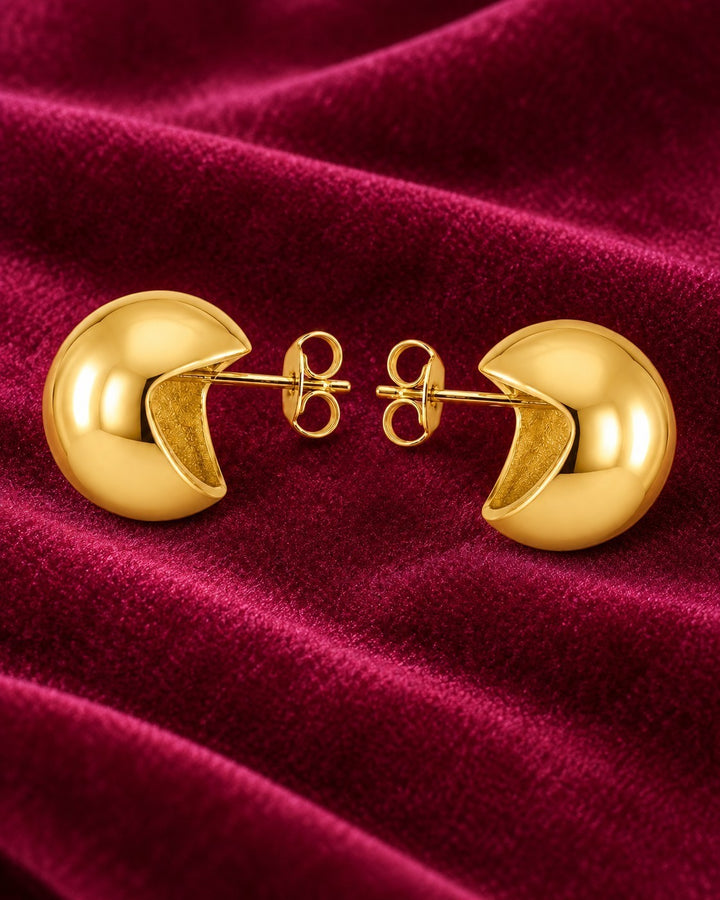 Elli Jewellery chunky dome stud earrings in 18ct gold plated metal with a polished crescent silhouette on red velvet.