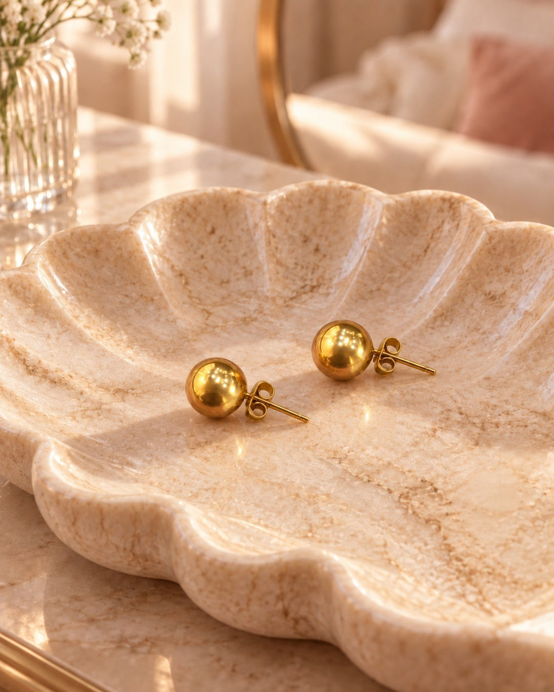 Elli Jewellery gold plated 8mm round dome stud earrings with a polished finish resting in a decorative marble dish.