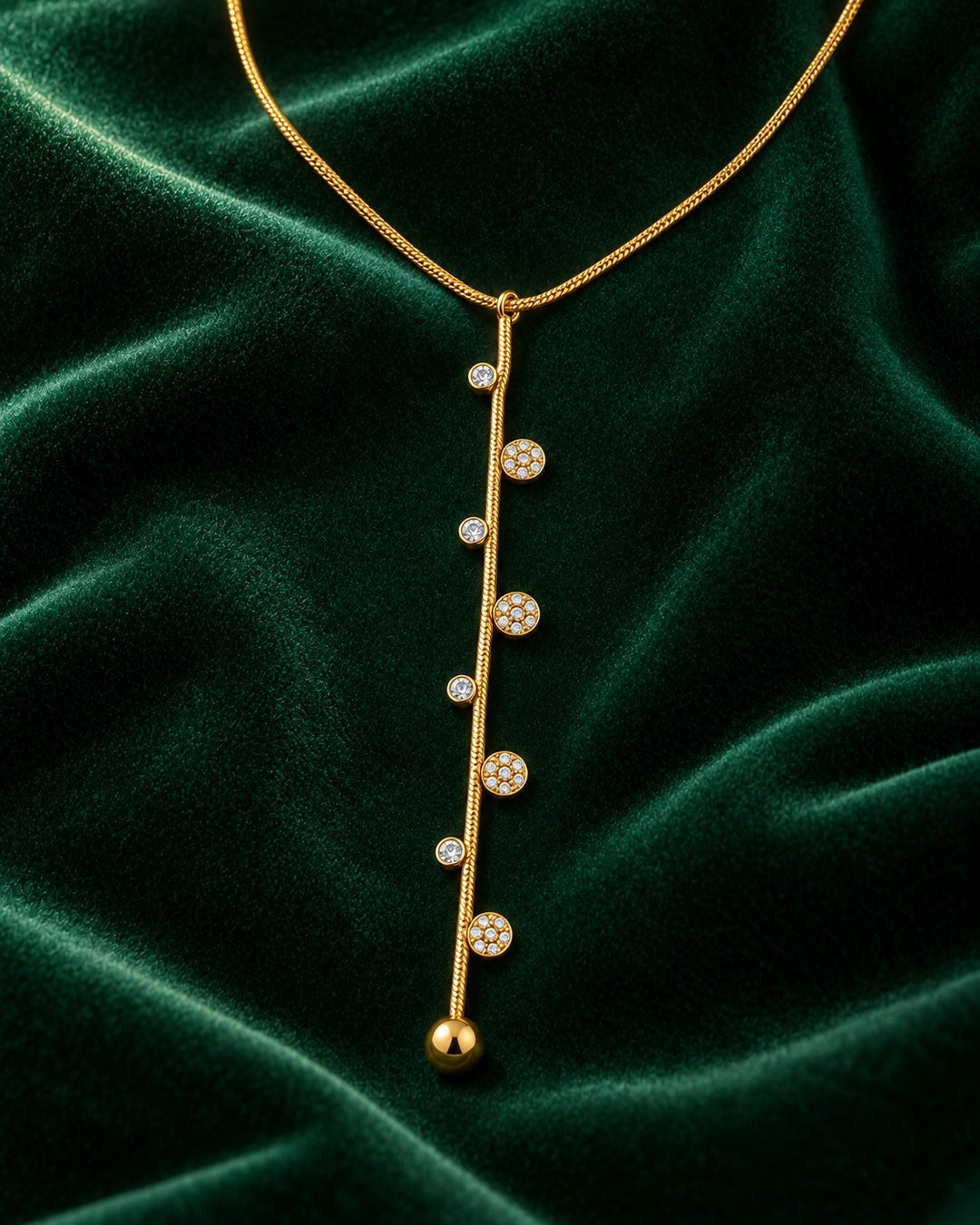 Elli Jewellery gold-plated dainty necklace featuring a vertical bar with delicate dotted crystal accents on green velvet.
