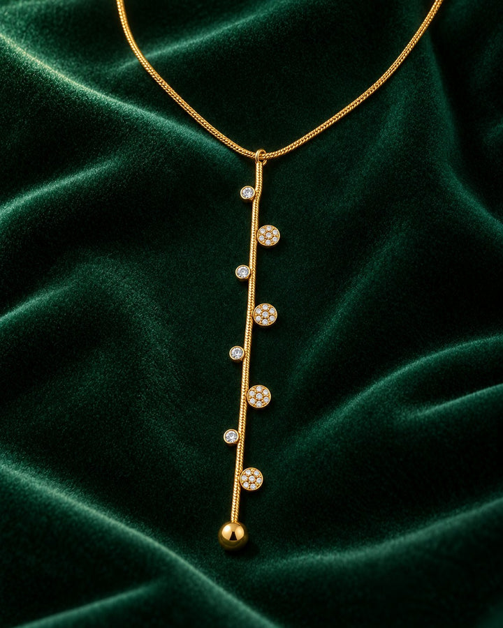Elli Jewellery gold-plated dainty necklace featuring a vertical bar with delicate dotted crystal accents on green velvet.